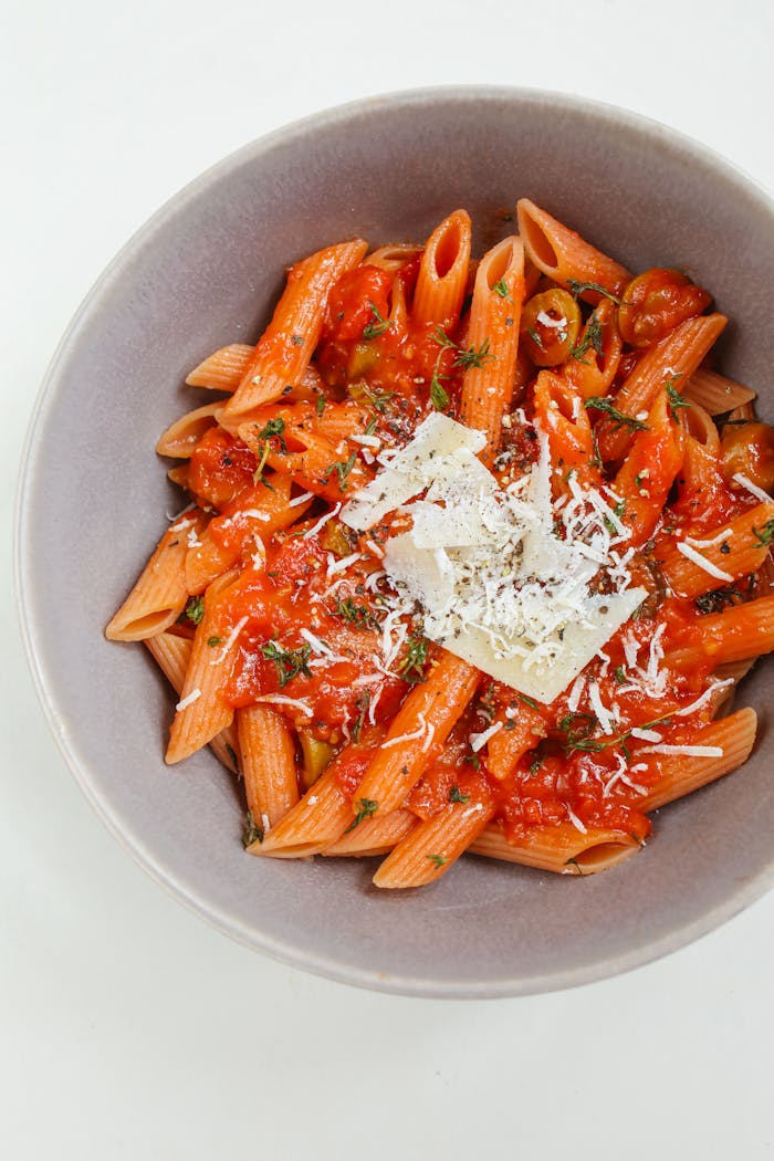 services-img Close-up of penne pasta in red tomato sauce topped with cheese, showcasing classic Italian cuisine.